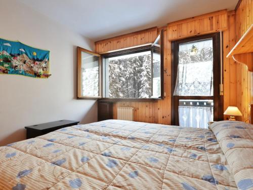 een slaapkamer met een bed en 2 ramen bij Apartment Des Alpes-8 by Interhome in Canazei