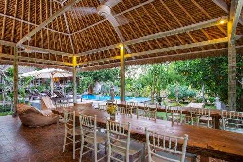 ein Esszimmer mit einem Tisch, Stühlen und einem Pool in der Unterkunft Komodo Garden in Nusa Lembongan