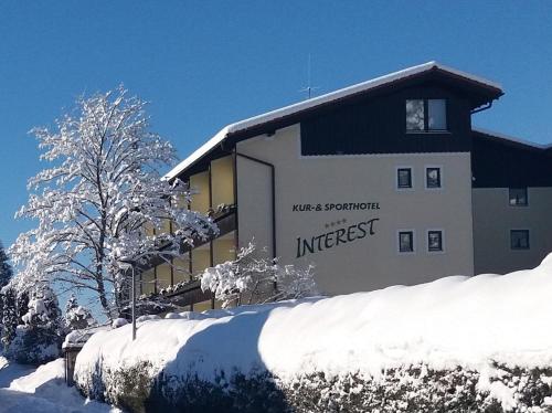 een gebouw met een bord in de sneeuw bij Interest Vitalhotel - Partnerbetrieb von Oberstaufen PLUS in Oberstaufen