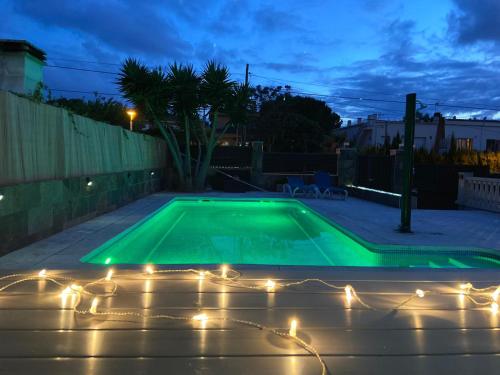 a swimming pool with lights in a backyard at night at Villa castelló salou in Salou