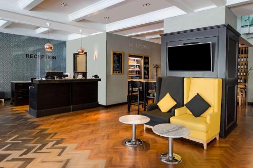 een winkel met een tv en een bank en kruk bij Park Inn by Radisson Bucharest Hotel & Residence in Boekarest