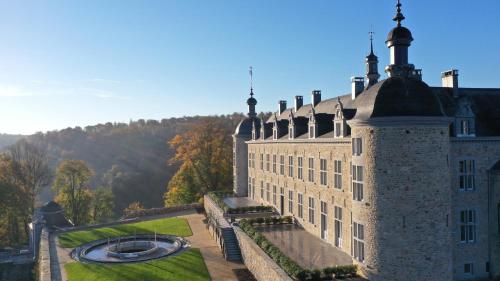 um grande castelo com uma fonte em frente em Le Château de Mirwart em Mirwart