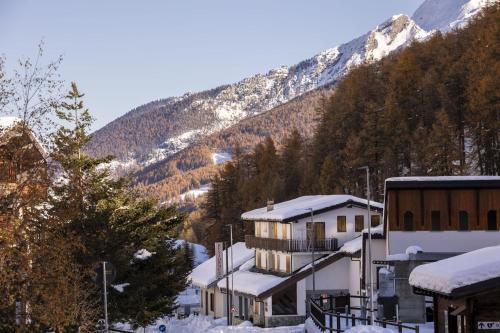 um edifício na neve com uma montanha ao fundo em Residence Nube D'Argento em Sestriere