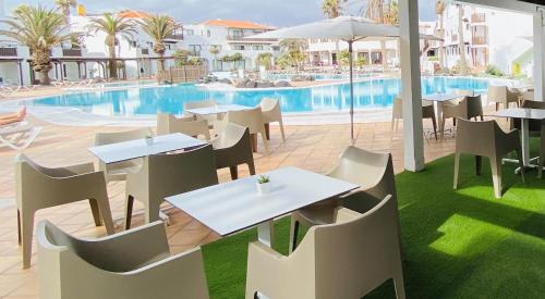 um restaurante exterior com mesas e cadeiras e uma piscina em Apartamentos Hesperia Bristol Playa em Corralejo