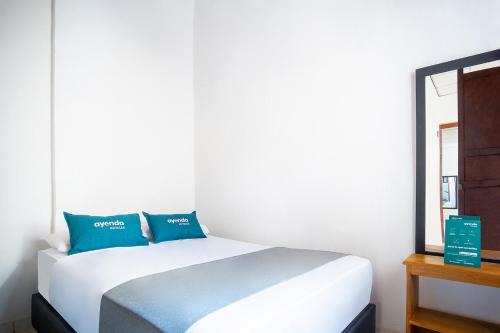 a white bed with blue pillows in a room at Ayenda Acacia in Ibagué