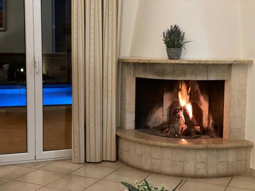 a fireplace in a living room with a fire in it at Corinthian Village in Vrahati