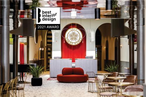 a lobby with a red couch and tables and chairs at Hotel Grand Koper in Koper