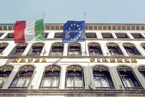 deux drapeaux sur le côté d'un bâtiment dans l'établissement Hotel Firenze, à Venise