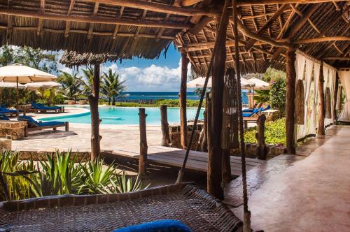 The Charming Lonno Lodge Watamu في واتامو: منتجع فيه مسبح وبه كراسي ومظلات