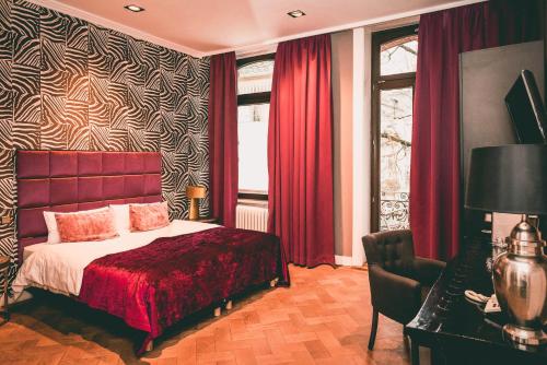 um quarto com uma cama, cortinas vermelhas e uma janela em Hotel Villa Klemm - Wiesbaden City em Wiesbaden