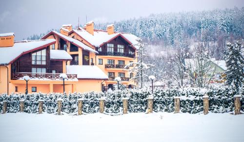 uma casa coberta de neve ao lado de uma cerca em СПА-Готель "RESPECT" em Skhidnitsa