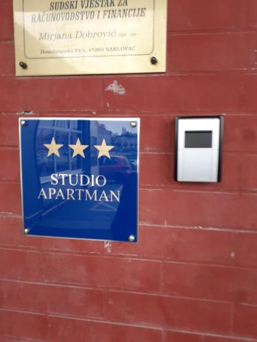 a sign on a red wall with a sign for a studio apartment at Apartment Apex penthouse self check-in in Karlovac