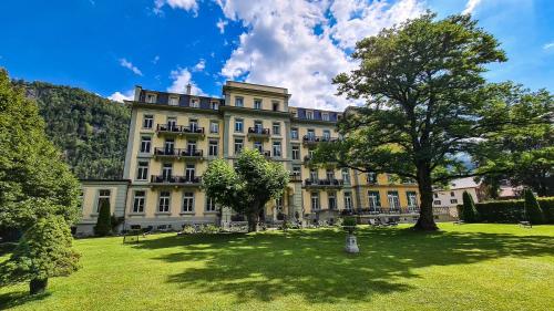 een groot gebouw met een gazon ervoor bij Parkhotel du Sauvage in Meiringen