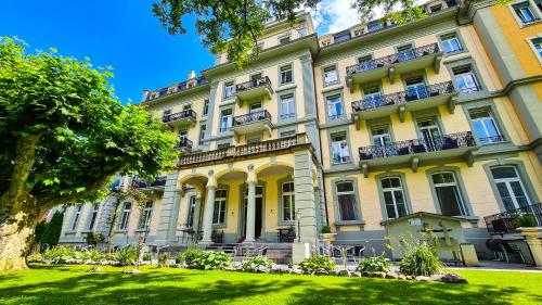 een groot geel gebouw met een gazon ervoor bij Parkhotel du Sauvage in Meiringen