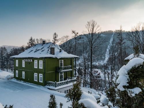 una casa verde con nieve encima en Willa Tęcza, en Szczawnica