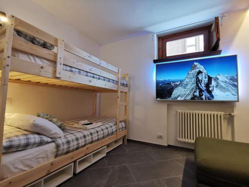 a bedroom with bunk beds and a tv on the wall at Aura Apartment - Ski In & Ski Out - Cerviniaholidays-com in Breuil-Cervinia