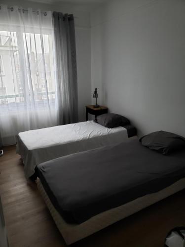 um quarto com 2 camas e uma janela em Bel appartement em Boulogne-sur-Mer