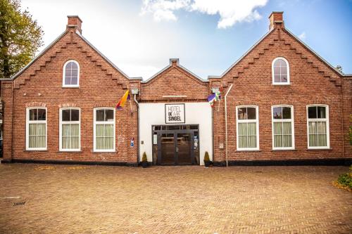 un gran edificio de ladrillo con una puerta grande en Hotel Aan De Singel, en Delfzijl