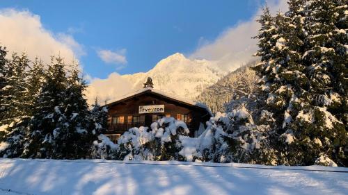 uma cabana de madeira na neve com árvores cobertas de neve em L'Arveyron Open House em Chamonix-Mont-Blanc