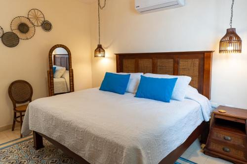 una camera da letto con letto, cuscini blu e specchio di Hotel & Hostal Boutique Casa Garza a Mérida