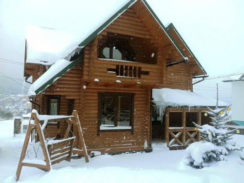 a log cabin with snow on the roof at Вілла Олекси in Skhidnitsa