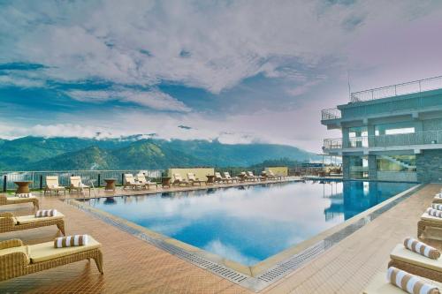 ムンナルにあるVibe Munnar Resort & Spaの大きなスイミングプール(椅子付)と建物