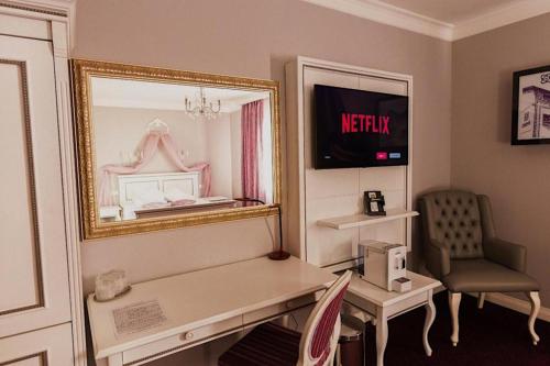 Cette chambre comprend un miroir, un bureau et une chaise. dans l'établissement 4Cardinal's Hotel Boutique, à Braşov