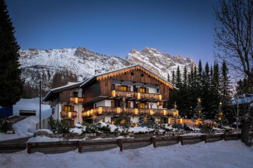 un edificio en la nieve frente a una montaña en Hotel Lajadira & Spa, en Cortina dʼAmpezzo