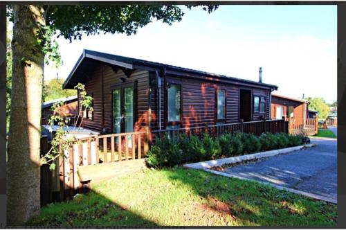 eine Blockhütte mit einer Veranda und einem Haus in der Unterkunft Brambles Holiday Lodges in Paignton