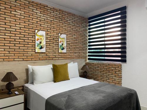 um quarto com uma cama e uma parede de tijolos em B & A Suites Inn Flats - Apart Flat Stratus em Anápolis