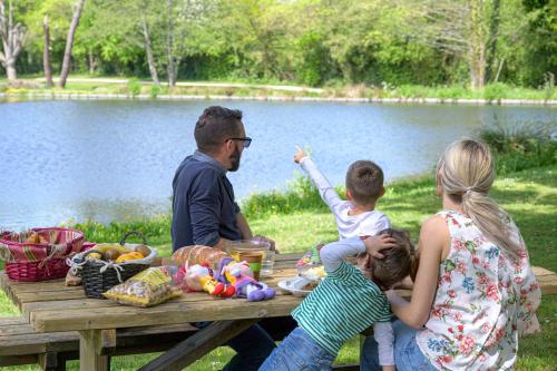 Camping Capfun La Bretèche في لي إيبيس: جلسة عائلية على طاولة نزهة بالقرب من البحيرة