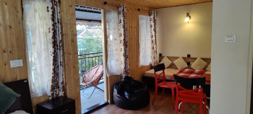 een kamer met een balkon met een tafel en stoelen bij The River View Homestay in Kurseong