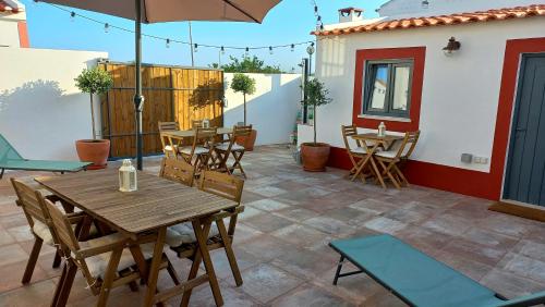 un patio con tavolo e sedie in legno e ombrellone di Cantinho de Milfontes 1 a Vila Nova de Milfontes