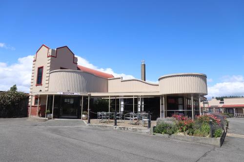 un edificio con tavoli e sedie in un parcheggio di The Village Inn Hotel a Te Anau