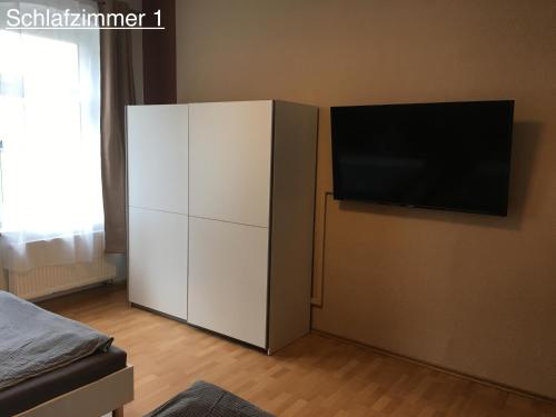 Elle comprend une armoire blanche dotée d'une télévision murale à écran plat. dans l'établissement Ferienwohnung RIENA, à Riesa