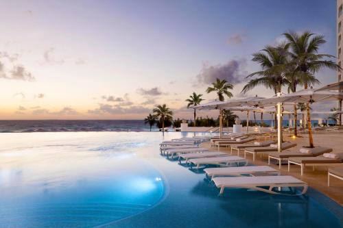 a hotel pool with chairs and umbrellas on the beach at Le Blanc Spa Resort Cancun - Adults Only - All-Inclusive in Cancún