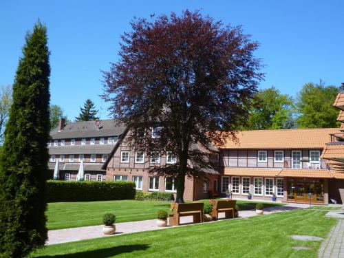 un bâtiment avec un arbre au milieu d'une cour dans l'établissement Hotel Hof Sudermühlen, à Egestorf