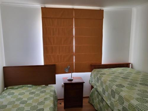 a bedroom with two beds and a lamp on a table at Casas Isla Negra in El Quisco