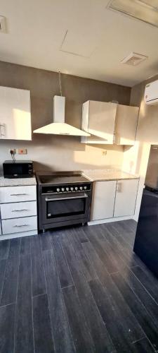 uma cozinha com armários brancos e um forno preto em HAVANA HOLIDAY HOMES MIRDIF no Dubai