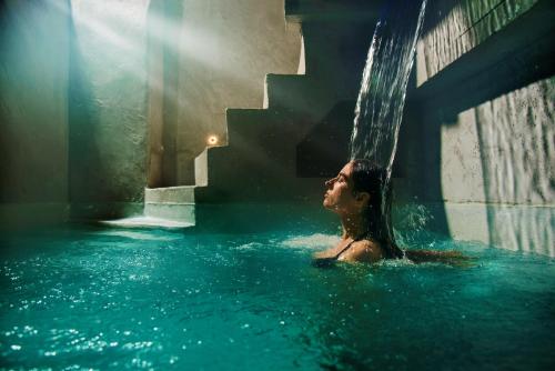 un homme dans une piscine sous une cascade dans l'établissement A.P. Acropolis View Apartments, à Athènes