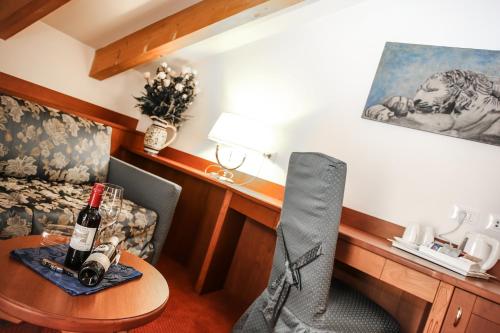 Cette chambre comprend un bureau et une table avec une bouteille de vin. dans l'établissement Sartori's Hotel, à Trente