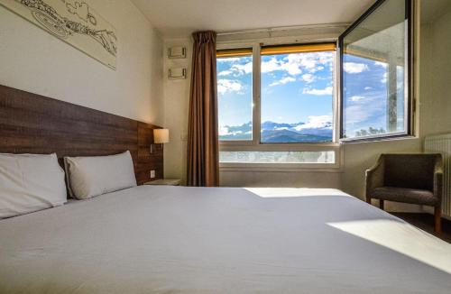 een slaapkamer met een groot bed en een raam bij The Originals Résidence, Grenoble Université in Saint-Martin-dʼHères