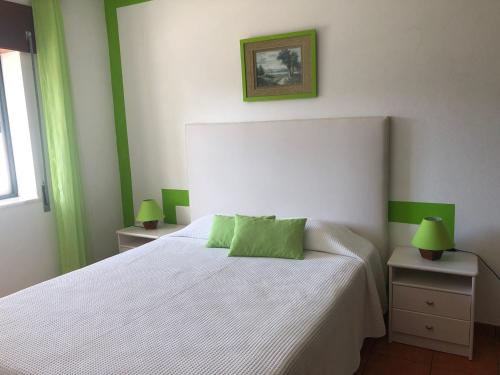 Un dormitorio con una cama blanca con detalles verdes en Camping Villa Park Zambujeira do Mar, en Zambujeira do Mar