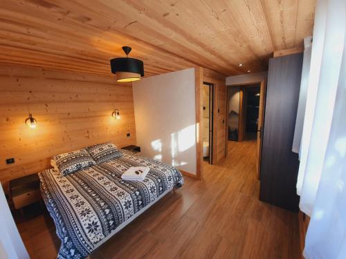 um quarto com uma cama e um tecto de madeira em Chalet Delphinette - Spa privatif em Morzine