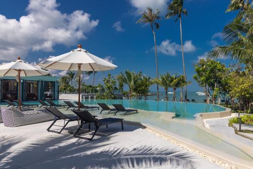 uma piscina com cadeiras e guarda-sóis numa praia em The Culture Samui em Bangrak Beach