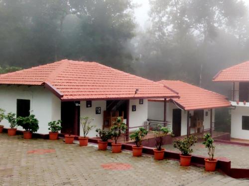 two houses with red roofs and potted plants in front at The Brown and Brew Homestay in Chikmagalūr