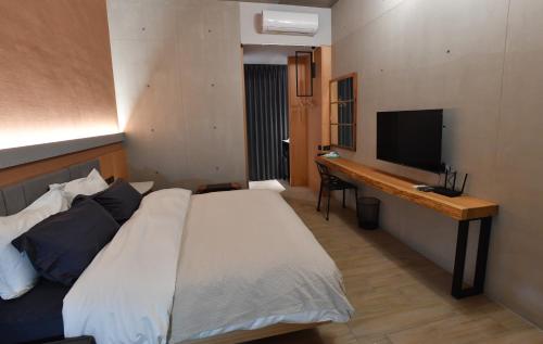 a bedroom with a bed and a desk with a television at Fu's house 52 in Tainan