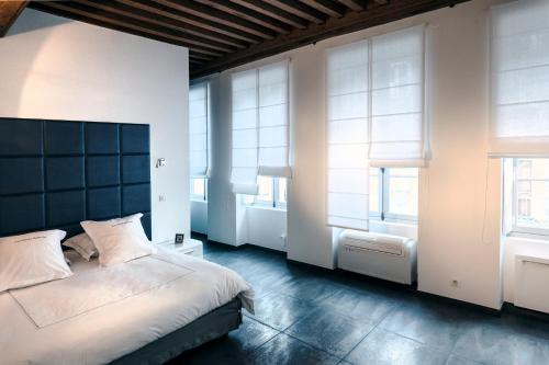 een slaapkamer met een groot bed en 2 ramen bij La Maison Blanche in Beaune