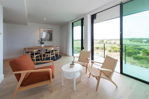 a living room with chairs and a table and windows at The Sands Torquay in Torquay