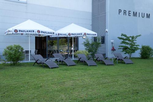 a group of chairs and umbrellas in front of a building at Star G Hotel Premium München Domagkstraße in Munich